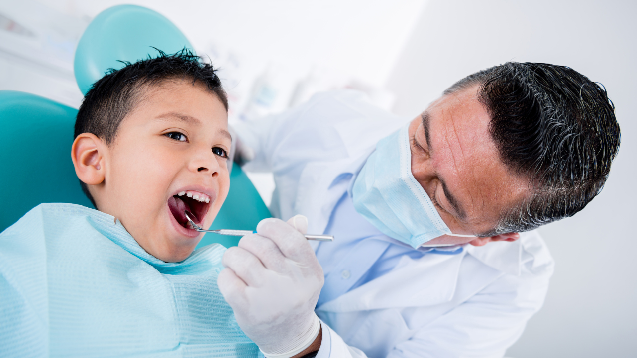 Closeup of a young boy in the dentist chair while a dentist inspects his mouth